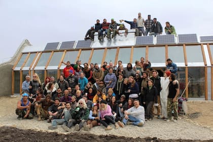 Los voluntarios que participaron de la academia y, detrás, la Earth Ship terminada