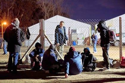 Lucas Castelli, ministro de Trabajo y Desarrollo Laboral de Neuquén, conversa con algunas de las personas en situación de calle que esperan para ingresar al lugar donde pasarán la noche
