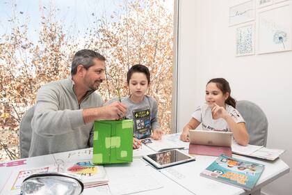 Luciano hace la tarea escolar con sus hijos. Aprendieron a dividir los tiempos para cada cosa en cuarentena