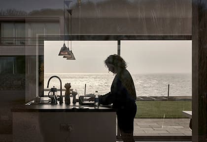 Lucy Ansbro en su casa en Thorpeness, Inglaterra, con vista al Mar del Norte y los acantilados que separan una hilera de casas de la playa. “Compré con el corazón en lugar de con la mente”, dijo.