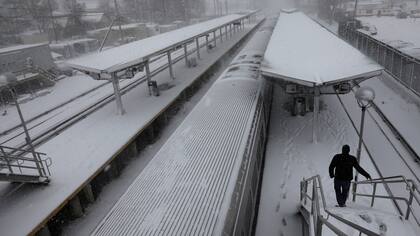 Un hombre camina sobre la plataforma cubierta de nieve del ferrocarril de Long Island en Port Washington