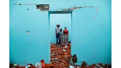 Luis Medina, de 36 años, trabajador rural, María Teresa Espinoza, de 35 años, ama de casa, y María de Jesús Medina, de 9 años, dentro de su casa que fue gravemente dañada después del terremoto en San José Platanar