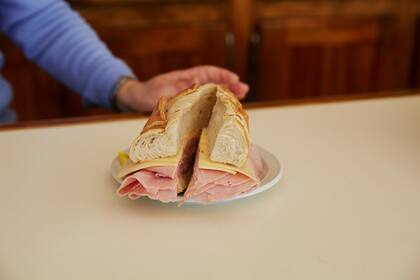 Mabel Di Santis y Daniel Rivera atienden el bar El Cruce, en Balcarce, famoso por su sandwich de jamón crudo y queso, el Titán de Balcarce del tamaño de un antebrazo. Su hijo Ignacio es la cuarta generación que atiende el lugar conocido por viajeros que también eligen las opciones de matambre y jamón cocido.