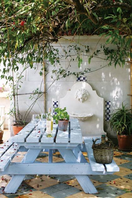 Macetas con más plantas contribuyen al clima fresco de la sombra. De fondo una fuente con un león en yeso decorada con mayólicas suma personalidad.