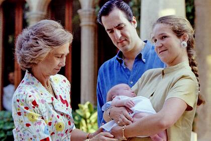 Agosto de 1998: la infanta Elena sostiene a su hijo, Felipe Juan Froilán de Todos los Santos, mientras que la reina Sofía le ajusta su ropa