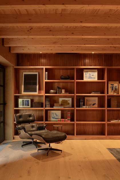 Madera, luz contenida y una biblioteca que acompaña el tiempo lento del trabajo y la lectura. El Eames Lounge Chair & Ottoman, diseño icónico de Charles y Ray Eames.