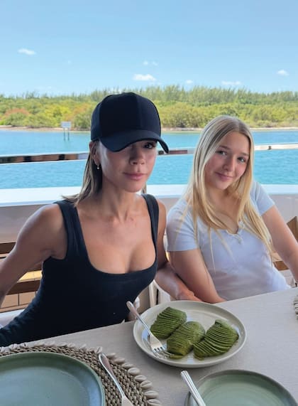 Madre e hija, con sonrisas y atuendos de verano en negro y blanco, almuerzan a bordo de su crucero