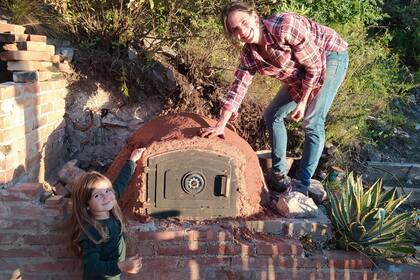 Madre e hija construyendo un horno de barro.