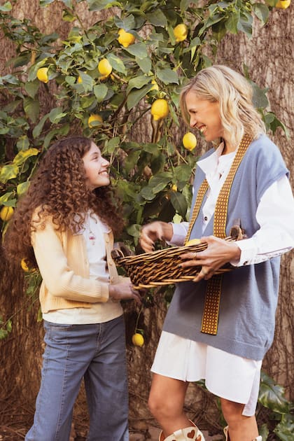 Madre e hija
recolectan los
limones del árbol que
tienen el jardín.