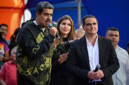 Maduro habla junto al empresario chavista Alex Saab durante el acto en Caracas por el aniversario del golpe que derrocó al dictador Pérez Jiménez (Photo by Gabriela Oraa / AFP)