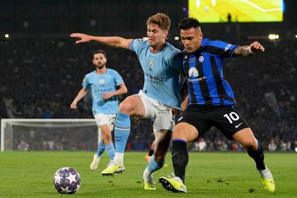 Manchester City's John Stones challenges for the ball with Inter Milan's Lautaro Martinez during the Champions League final soccer match between Manchester City and Inter Milan at the Ataturk Olympic Stadium in Istanbul, Turkey, Saturday, June 10, 2023. (AP Photo/Emrah Gurel)