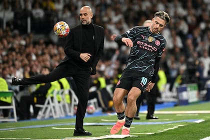 Manchester City's Spanish manager Pep Guardiola (L) controls the ball at the touchline during the UEFA Champions League quarter final first leg football match between Real Madrid CF and Manchester City at the Santiago Bernabeu stadium in Madrid on April 9, 2024. (Photo by JAVIER SORIANO / AFP)
