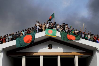 Manifestantes antigubernamentales muestran la bandera nacional de Bangladesh mientras irrumpen en el palacio de la primera ministra Sheikh Hasina en Dacca el 5 de agosto de 2024.