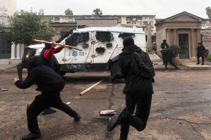 Manifestantes chocan con la policía durante una marcha que conmemora el 50 aniversario del golpe militar de 1973 liderado por el general Augusto Pinochet, en el Cementerio General de Santiago, Chile, el domingo 10 de septiembre de 2023. (Foto AP/Luis Hidalgo)