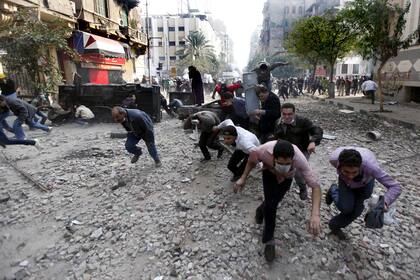Manifestantes corren a cubrirse durante los enfrentamientos con la policía antidisturbios egipcia cerca de la plaza Tahrir en El Cairo, Egipto, el 22 de noviembre de 2011