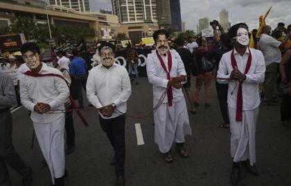 Manifestantes de Sri Lanka llevan máscaras de los miembros de la familia del presidente Gotabaya Rajapaksa durante una marcha que exige la dimisión de Gotabaya, en el lugar de la protesta en curso en Colombo, Sri Lanka, 29 de abril de 2022.