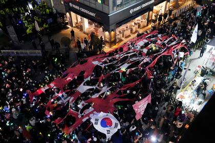 Manifestantes desgarran un estandarte que representa el Partido del Poder Popular (PPP) durante una marcha para exigir que el presidente surcoreano Yoon Suk Yeol enfrente juicio político, frente a la sede del PPP en Seúl, Corea del Sur, el lunes 9 de diciembre de 2024. (AP Foto/Ahnn Young-joon)