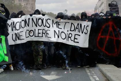 Manifestantes en París con un cartel que dice "Macron nos enfurece"