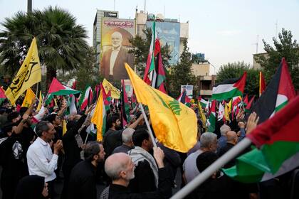 Manifestantes iraníes ondean banderas iraníes, palestinos y del grupo terrorista Hezbollah tras el asesinato del líder de Hamas Ismail Haniyeh