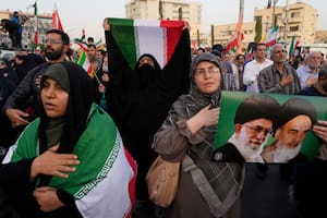 Manifestantes iraníes sostienen banderas del país y un cartel del ayatollah Khomeini y del actual líder supremo, Ali Khamenei