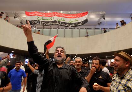 Manifestantes iraquíes posan con banderas nacionales dentro del edificio del parlamento en Bagdad, Irak, el domingo 31 de julio de 2022. 