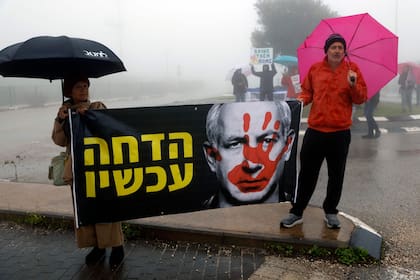 Manifestantes israelíes sostienen una pancarta con el Primer Ministro Benjamin Netanyahu durante una manifestación antigubernamental frente a la escuela Ramat Chorazim en Moshav Elifelet, en el norte de Israel, el 23 de enero de 2024.
