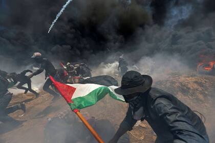 Manifestantes palestinos huyen del fuego israelí y del gas lacrimógeno durante la protesta contra el traslado de la embajada de EE. UU. A Jerusalén