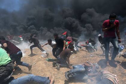 Manifestantes palestinos huyen del fuego israelí y del gas lacrimógeno durante la protesta