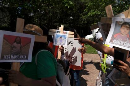 Manifestantes portan cruces con fotografías de víctimas de la masacre en la Escuela Primaria Robb de Uvalde, Texas, durante una protesta contra la convención de la Asociación Nacional del Rifle