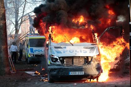 Manifestantes prenden fuego a un autobús de la policía en el parque Sveaparken en Orebro, Suecia, el viernes 15 de abril de 2022. (Kicki Nilsson/TT vía AP)