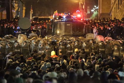 Manifestantes se enfrentan a la policía antidisturbios georgiana que forma un cordón cerca del Parlamento georgiano en Tiflis el 7 de marzo de 2023.