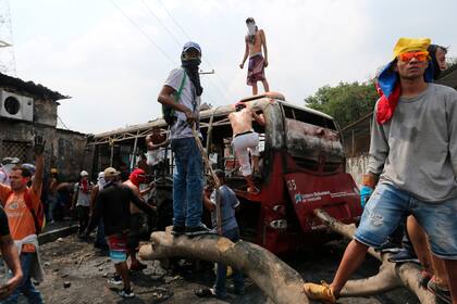 Manifestantes se paran en un autobús incendiado durante los enfrentamientos con la Guardia Nacional Bolivariana en Urena, Venezuela, cerca de la frontera con Colombia.