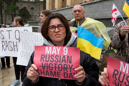 Manifestantes sostienen carteles durante una protesta antibélica contra la invasión rusa de Ucrania en Tiflis, Georgia, el domingo 8 de mayo de 2022, un día antes de que Rusia celebre el Día de la Victoria, que marca los 77 años de la victoria en la Segunda Guerra Mundial.