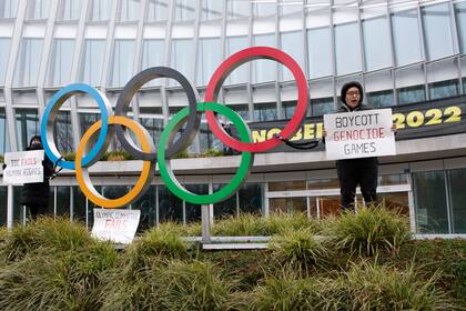 Manifestantes sostienen letreros durante una protesta contra la realización de los Juegos Olímpicos de Invierno de Beijing de 2022, frente a la sede del Comité Olímpico Internacional, en Lausana, Suiza, el sábado 11 de diciembre de 2021. (Jean-Guy Python/Keystone vía AP)