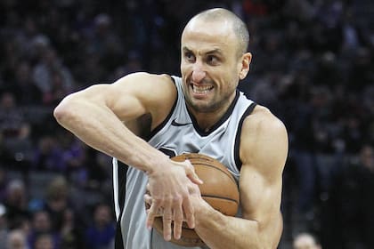 Manu Ginobili pasa pordetras de George Hill de Sacramento Kings durante la segunda mitad de un partido de baloncesto de la NBA en Sacramento, California, el sábado 23 de diciembre de 2017. Los Spurs ganaron 108-99