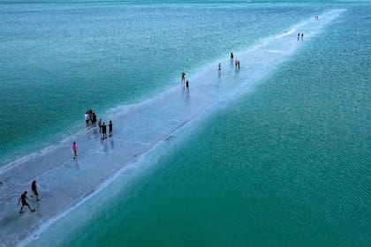 Personas caminando sobre tierra de sal entre estanques de evaporación en la parte sur del Mar Muerto, donde tanto el cloruro de sodio como las sales de potasio son producidas por las fábricas de Dead Sea Works, cerca del complejo israelí Neve Zohar.