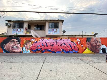 Maradona, Messi y Pelé, reunidos en un mural sobre la avenida 25 de Julio, en Guayaquil. Junto a ellos, la firma de Abser, uno de los artistas detrás de la obra.