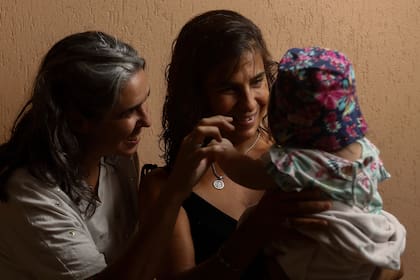 Marcela (de negro) y Micaela comparten con sus familias la tarea de cuidar a la pequeña beba de forma transitoria; integran Comunidad Malú, una organización social de familias de abrigo de La Plata 