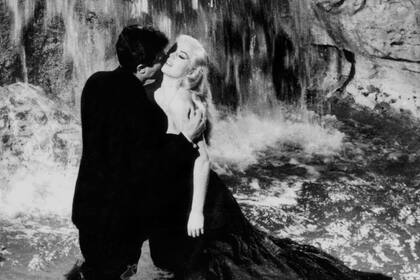 Marcello Mastroianni y Anita Ekberg en la Fontana di Trevi, la memorable escena de La dolce vita de Federico Fellini, que legó a la posteridad la palabra paparazzo para describir el trabajo de los reporteros de la farándula