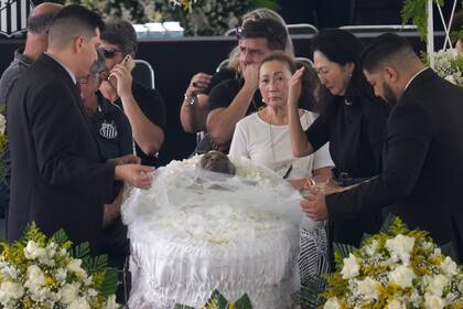 Marcia Aoki, the widow of Brazilian soccer great Pele, mourns over his body that lies in state at Vila Belmiro stadium during his wake in Santos, Brazil, Monday, Jan. 2, 2023. (AP Photo/Andre Penner)