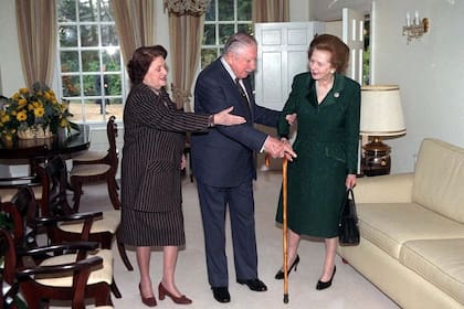 Margaret Thatcher, ex primera ministra británica (a la derecha), se reúne con Augusto Pinochet y su esposa Lucía Hiriart (a la izquierda), el viernes 26 de marzo de 1999 en la residencia alquilada del general en Wentworth, Inglaterra, a unos 40 kilómetros de Londres. Dos días antes, el máximo tribunal británico había resuelto que Pinochet no tenía inmunidad absoluta como ex jefe de Estado. Thatcher había apoyado públicamente la liberación del ex dictador, detenido en Londres por una orden de extradición española que buscaba juzgarlo por violaciones a los derechos humanos cometidas durante su gobierno. (Foto: AP/Ian Jones, Pool).