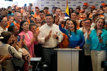 María Corina Machadoy Freddy Superlano, ambos al centro, levantan los brazos para los fotógrafos durante un evento de campaña en Caracas, Venezuela, el viernes 13 de octubre de 2023.