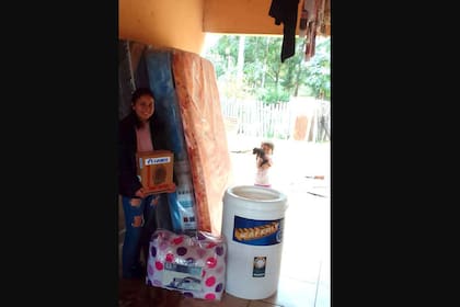 María posa junto al lavarropas, el caloventor, los colchones y el resto de las cosas que pudo comprar gracias a las donaciones recibidas