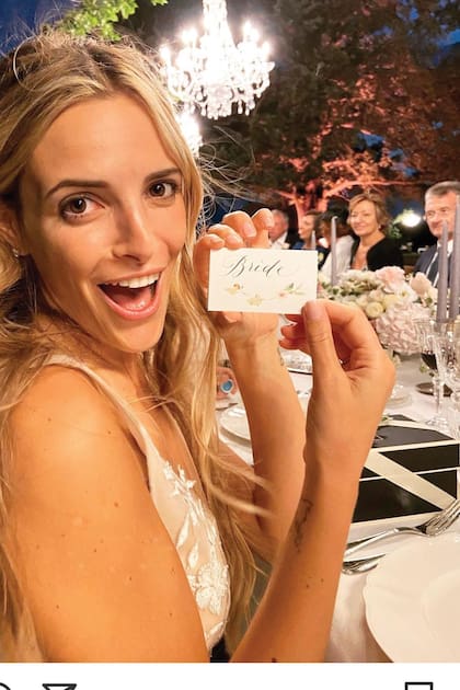 María sonríe divertida mientras muestra el cartelito con la leyenda “Bride” (novia), ubicado en la mesa