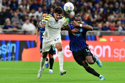 Mariano Troilo lucha por la pelota con Ange-Yoan Bonny (14), mientras Lautaro Martínez observa la jugada detrás, en Inter - Parma, por la Serie A