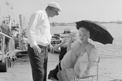 Marilyn Monroe, protegiéndose del sol con un paraguas, habla con el director Billy Wilder durante la grabación de "Some Like It Hot", el 20 de octubre de 1958.