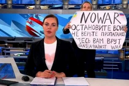 This video grab taken on March 15, 2022 shows Russian Channel One editor Marina Ovsyannikova holds a poster reading " Stop the war. Don't believe the propaganda. Here they are lying to you"  during on-air TV studio by news anchor Yekaterina Andreyeva , Russia's most-watched evening news broadcast, in Moscow on March 14, 2022 . - As a news anchor Yekaterina Andreyeva launched into an item about relations with Belarus, Marina Ovsyannikova, who wore a dark formal suit, burst into view, holding up a hand-written poster saying "No War" in English. (Photo by Handout / AFP) / RESTRICTED TO EDITORIAL USE - MANDATORY CREDIT "AFP PHOTO / Channnel One  - NO MARKETING NO ADVERTISING CAMPAIGNS - DISTRIBUTED AS A SERVICE TO CLIENTS