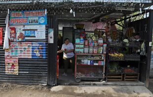 Maritza Pacheco trabaja en la pequeña tienda de comestibles que abrió cuatro meses antes, fuera de su casa en el barrio Primero de Diciembre en Soyapango, El Salvador, el jueves 2 de marzo de 2023. 