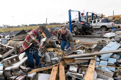 Martin Bolton (izq.) Y el dueño de la tienda Danny Wagner intentan apagar un medidor de gas con fugas después de que su taller de reparación de automóviles fuera destruido por un tornado en Mayfield, Kentucky, el 11 de diciembre de 2021. -