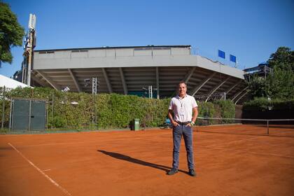 Martín Hughes, ejecutivo de Tennium, en una de las canchas de entrenamiento, con la tribuna del court central del BALTC de fondo